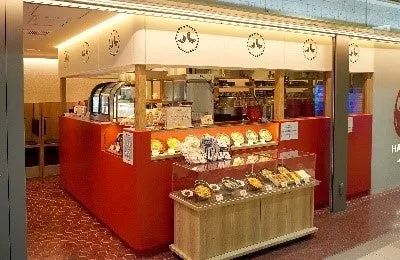 ショッピングモール内の赤いカウンターが目立つHACHIKIのテイクアウト向け小型店舗外観。ショーケースに惣菜が並ぶ