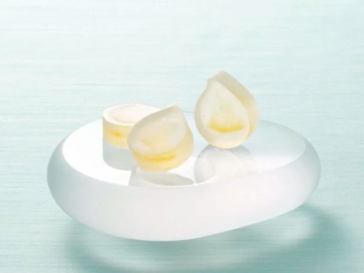 琥珀糖「レモンの雫」2個を白い丸皿に乗せた商品アップショット。水滴形の半透明白×レモンイエローの断面が確認できる