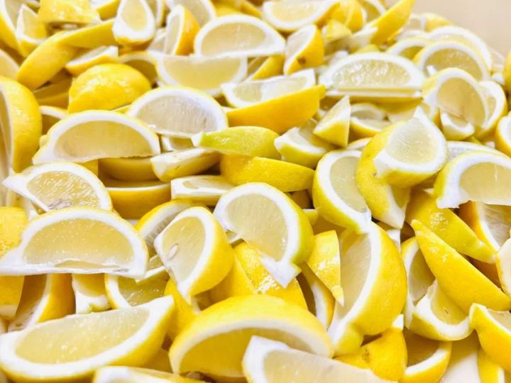 琥珀糖の原料となる国産レモンをくし形にカットして大量に並べた素材ショット。果肉の黄色と白い内皮のコントラストが前面に出た製造工程を示す俯瞰写真