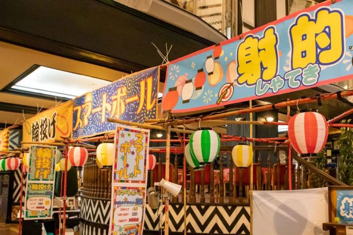 屋内に設けられた縁日コーナーで輪投げ・スマートボール・射的の屋台看板と提灯が並ぶイベント会場の設営状況