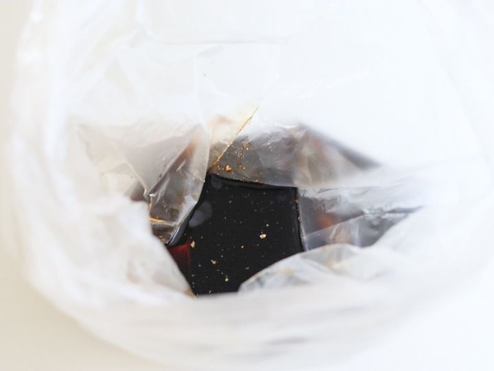 白いビニール袋に砂糖・しょうゆ・酒・塩・黒こしょう・おろしにんにくを入れて混ぜ合わせている様子