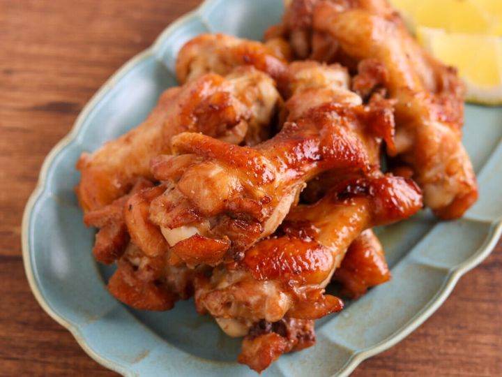 青緑色の波型プレートにこんがり焼き色のついた手羽元を盛りレモンのくし切りを添えた完成写真