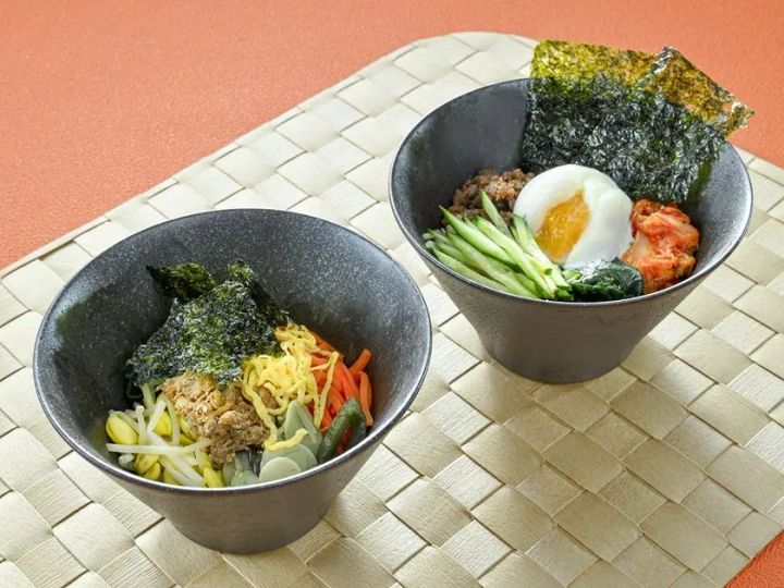 2種類のビビンバ丼をグレーの石目調ボウルに盛った料理写真。左は野菜中心の混ぜご飯、右は半熟卵・キムチ・海苔をトッピングしたスパイシー系の構成