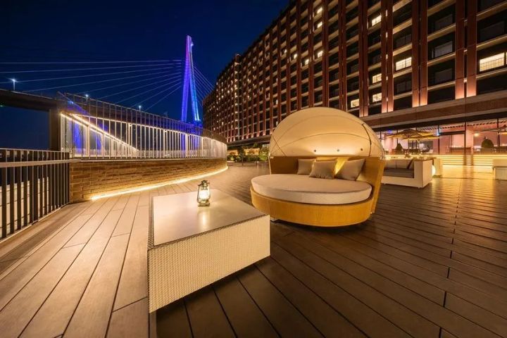 リーベルホテル大阪の屋外テラスデッキを夜景とともに撮影。ドーム型ソファとランタン、ライトアップされた斜張橋を背景に収めたホテル施設の外観ショット