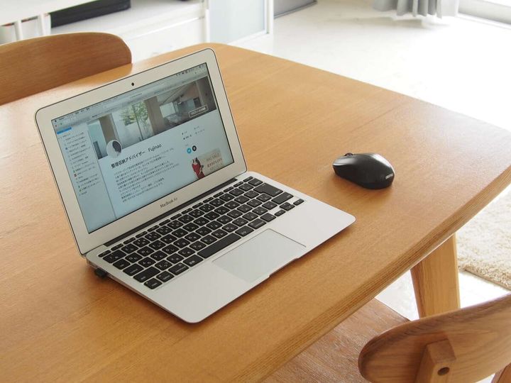 木製ダイニングテーブルの上にMacBook Airとワイヤレスマウスが置かれている斜め俯瞰の写真