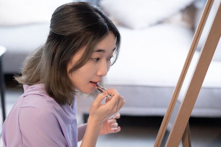鏡を見ながら口紅を塗る若い日本人女性