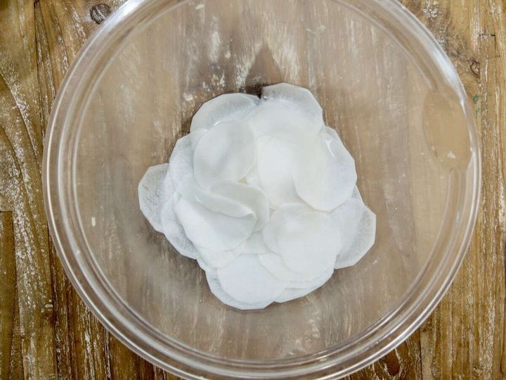 薄くスライスした白いカブを透明なガラスボウルに入れた俯瞰写真