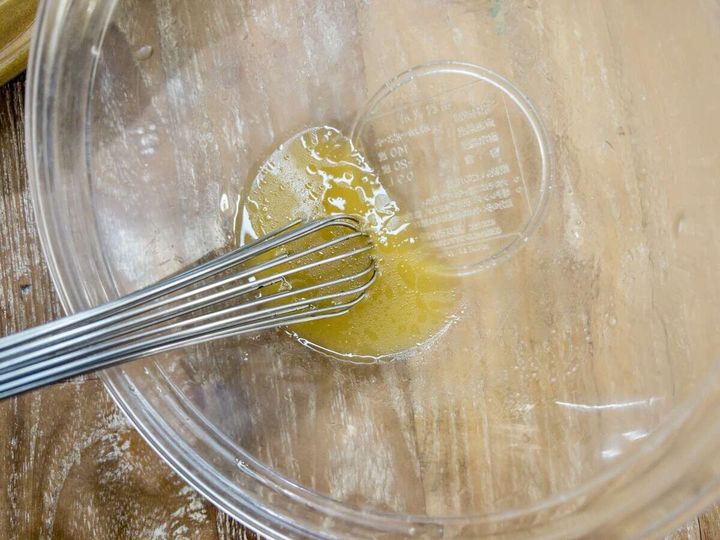 ガラスボウルの中で泡立て器を使いドレッシングを混ぜて乳化させている俯瞰写真