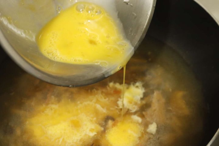 ダイソーのニチレイ 酸辣湯に溶き卵を加えて調理する様子
