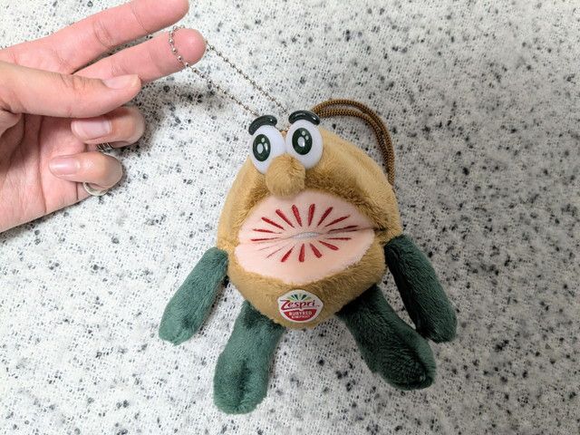 キウイブラザーズぬいぐるみチャームのアップ。全長12cm、幅7cmのかわいいサイズ感