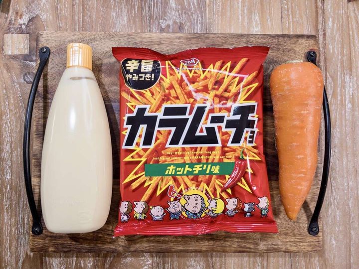人参ムーチョの材料。マヨネーズのボトル、赤いパッケージの湖池屋スティックカラムーチョ ホットチリ味、人参1本が木製トレイに並んでいる