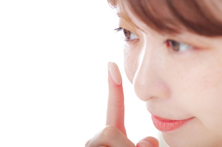 肌に下地やファンデーションを指で塗る女性 美容イメージ