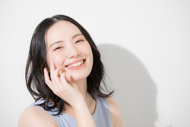 スキンケア 頬に手を添える笑顔の女性 美容イメージ美容イメージ