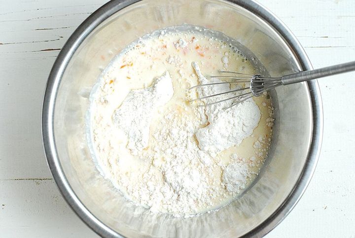 ステンレスボウルにホットケーキミックスと牛乳、溶き卵を入れて泡立て器で混ぜ始めている俯瞰写真