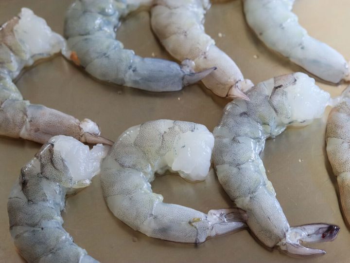 殻をむき背ワタを取った生エビをトレーに並べたアップ写真