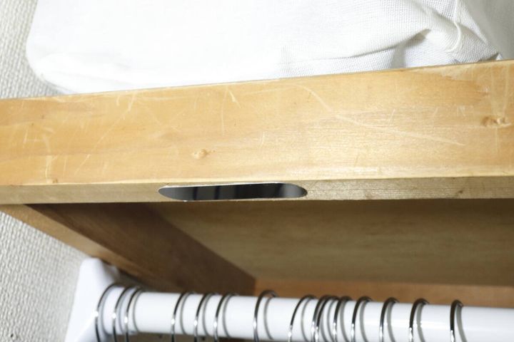 クローゼットの木製棚板の裏側に細長い黒い金属パネルを貼り付けた様子。下にハンガーパイプが見える