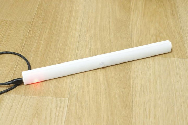 木目の床に置いた本体にType-Cケーブルをつないで充電している写真。端の赤いLEDが点灯している