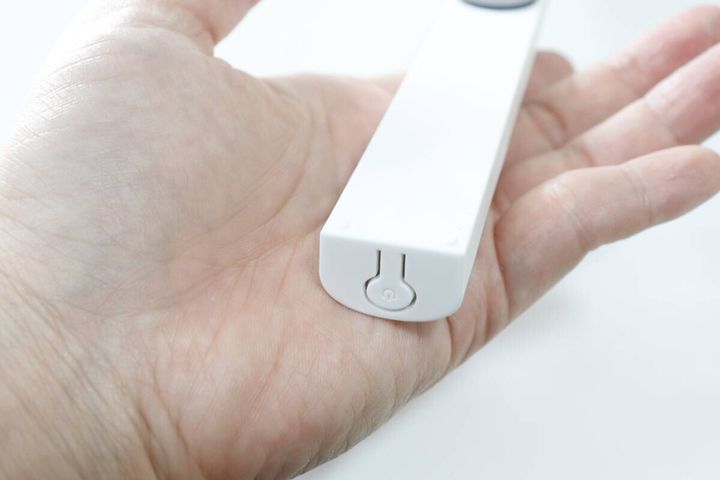 手のひらに乗せた本体の端のアップ。電源マークが刻印された電源スイッチが見える