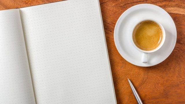 机の上のノートとコーヒー