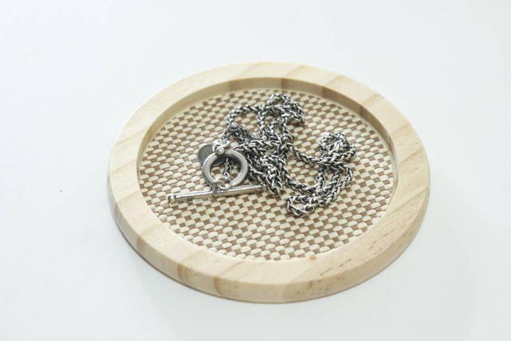 セリアの白木メッシュコースター 茶 丸にアクセサリーを置く
