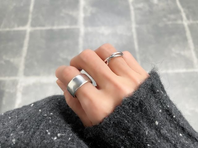 大ぶりと小ぶりのリングを１つずつつけた女性の手元 アクセサリー