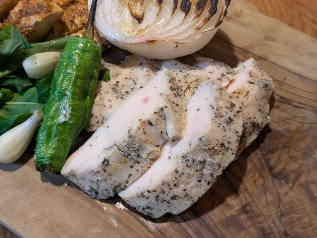 三宿ソルトチキンのカット断面。ハーブの香るやわらかなチキンにグリル野菜を添えたまな板の上の盛り付け