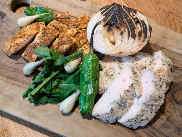 2種のローストチキン（プレーンとスパイス）に野菜を添えてまな板に並べた盛り付け例。チキンの色の違いがわかる