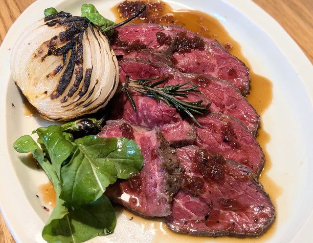 赤城牛ローストビーフを白いプレートに盛り付けた料理写真。ローズマリーと焼き玉ねぎ、グリーンリーフを添えたスタイリッシュな一皿
