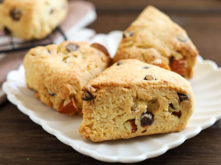 白い皿に盛り付けたアーモンドとチョコチップ入りの三角形スコーン