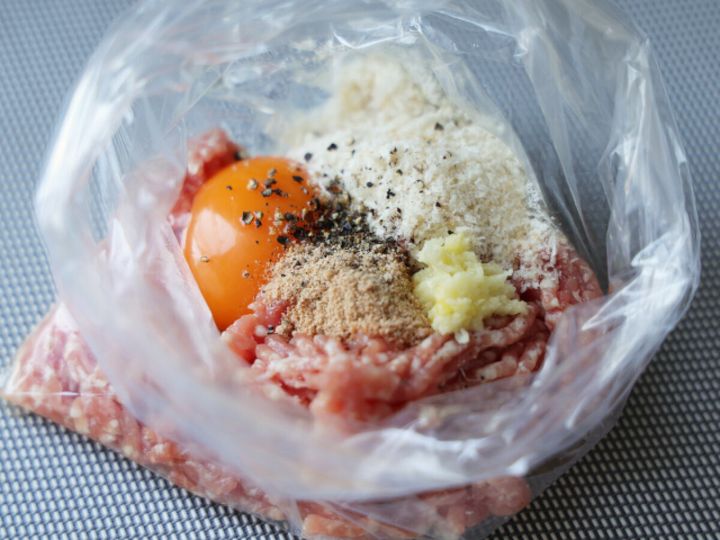ビニール袋にひき肉・卵・パン粉・すりおろしにんにく・黒こしょうを入れた肉だねの材料のアップ俯瞰写真