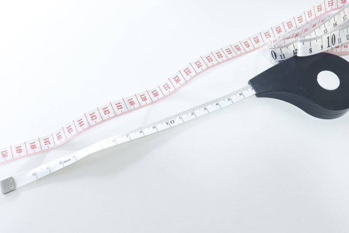 白いフラットメジャーのテープを長く引き出して広げている