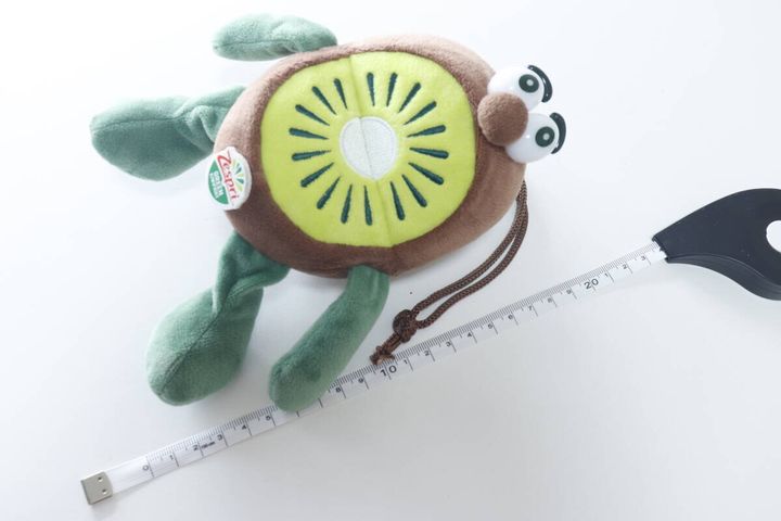 キウイのぬいぐるみの横にフラットメジャーを置いてサイズを測っている
