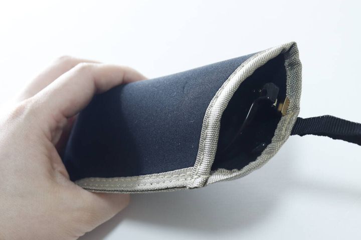 女性の手がダイソー眼鏡ケースにサングラスを入れている