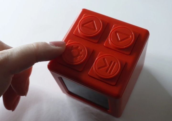赤いブロック型デジタルタイマー時計のボタンを指で押している様子