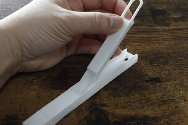 白いサッシ用ほうきを右手が持ち、ちりとりから引き抜こうとしている
