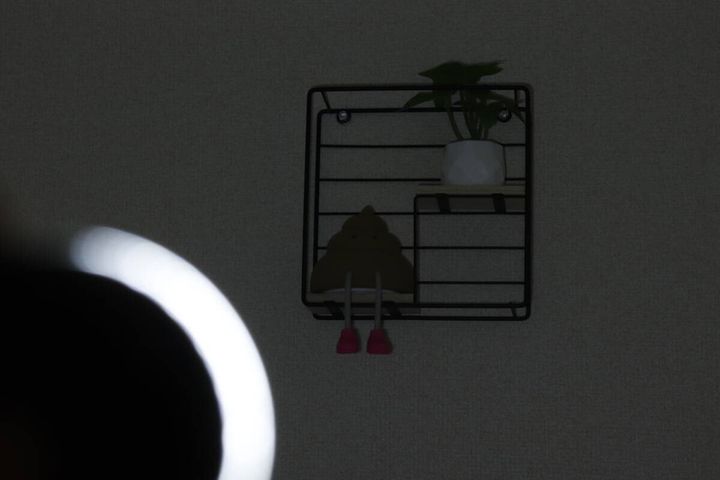 暗い部屋でライトのCOBモードLowを壁の棚に当てて薄暗く照らしている