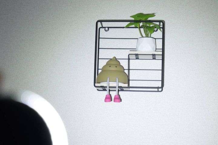 暗い部屋でライトのパワーモードを壁の棚に当てて明るく照らしている