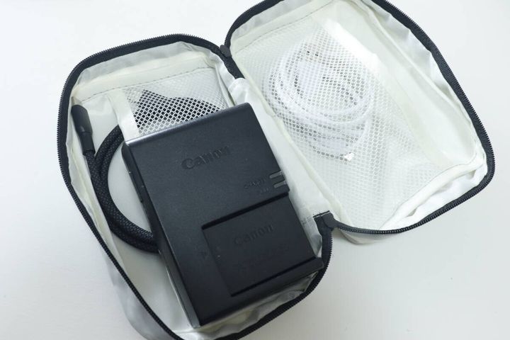 グレーのポーチにカメラバッテリーと充電ケーブルを収納している様子