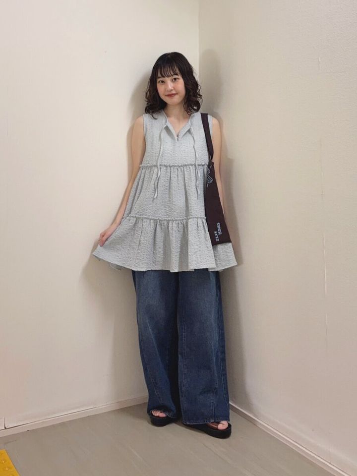 ブルーのティアードチュニックと濃いめワイドデニムの女性