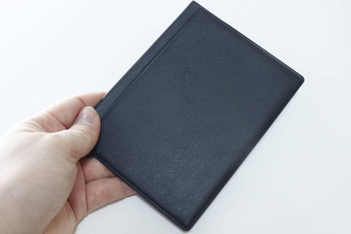 黒いパスケースを手に持ち、薄さとサイズ感を示している
