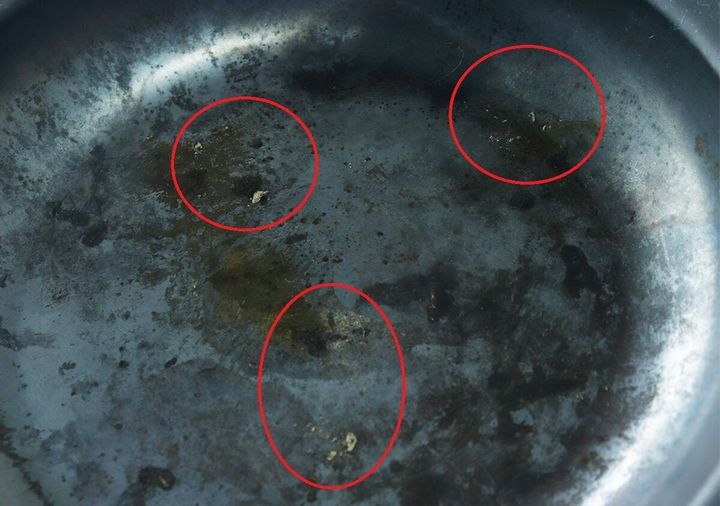 焦げ付きや油汚れが付着したフライパンの底を赤丸で囲んでいる