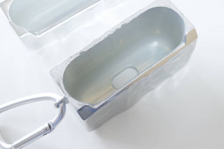 シルバーのメッキ色イヤホンケースを開き、内側を見せた状態