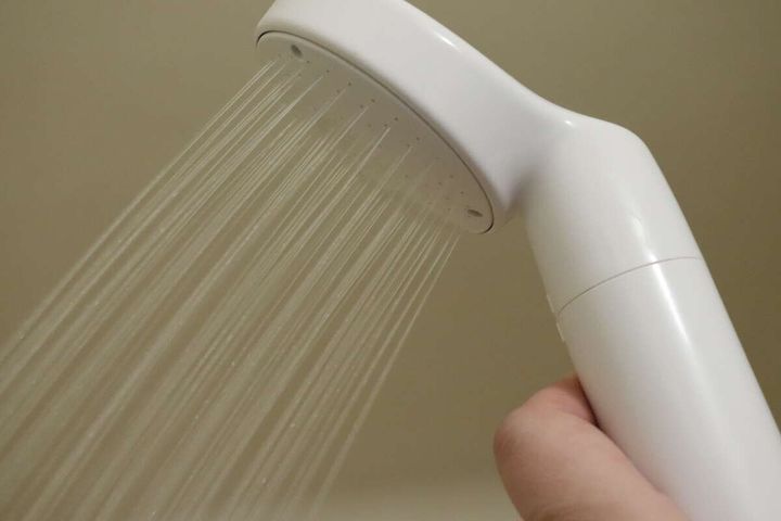 浴室で白いシャワーヘッドから水が出ている様子