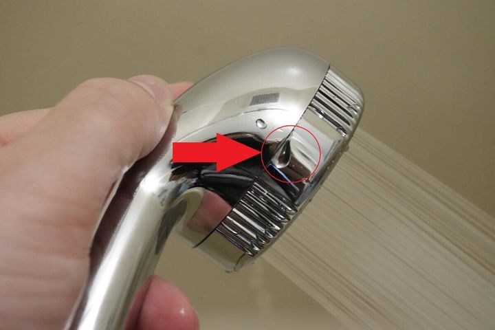 シャワーヘッドの接続部分から水漏れしている箇所を赤丸と矢印で示している