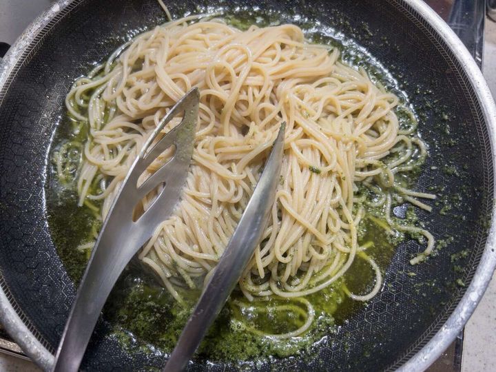 フライパンの中でしそベーゼソースと茹でたパスタをトングで和えている様子