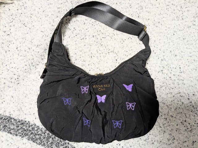 ANNA SUI mini 2wayクロワッサンバッグ正面。ブラックのクシュ素材に蝶の刺繍と立体パーツが散りばめられている