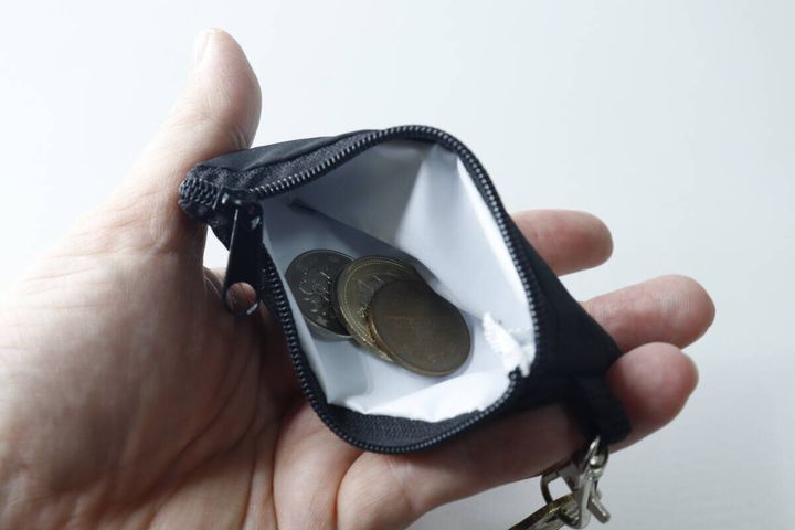 開いた黒いミニポーチに、数枚の小銭が入っている様子。