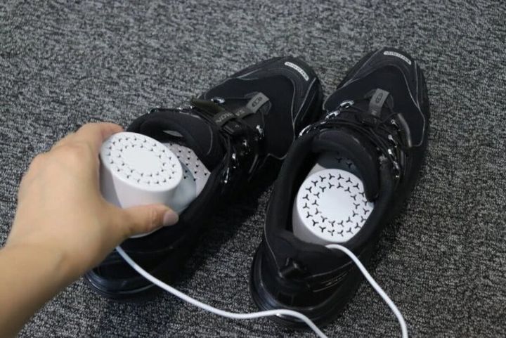 黒いスニーカーに白いシューズドライヤーを差し込む手元