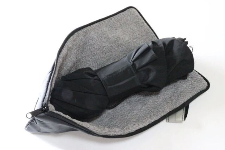 広げた傘カバーの内側に黒い折り畳み傘を入れている