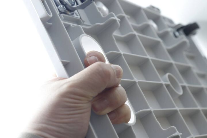白いキャリー台車の裏側にある持ち手部分を指で掴んでいる